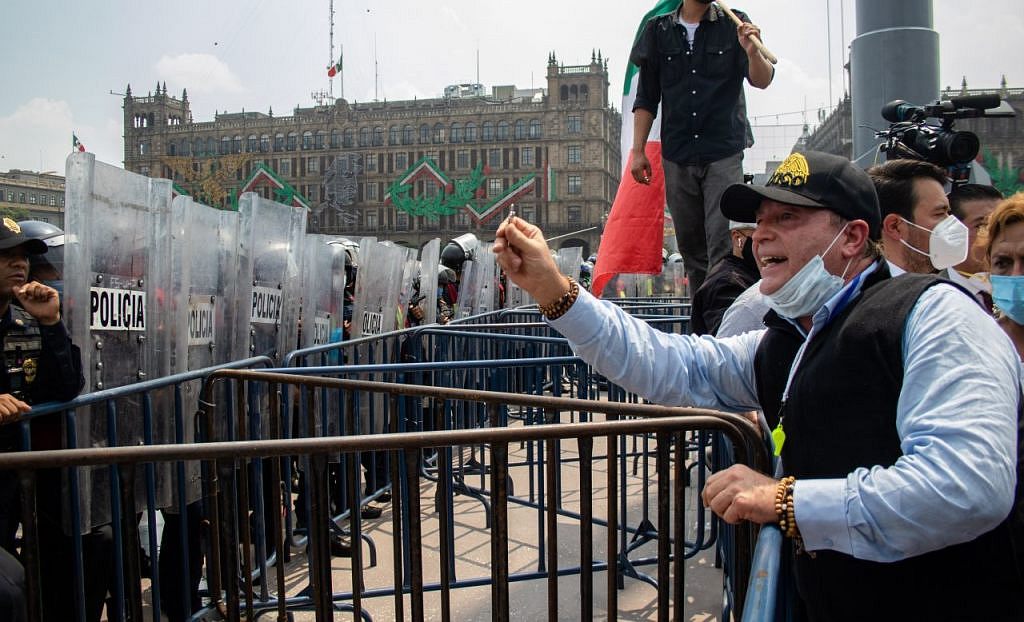 Gilberto Lozano, líder del Frente Nacional Anti-AMLO (FRENAAA), con un crucifijo en mano bendice a los granaderos que mantienen resguardando la plancha del zócalo