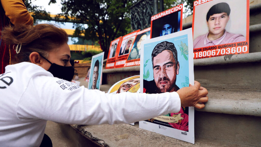 mujer acomoda la foto de un familiar para reclamar en México desaparición de personas