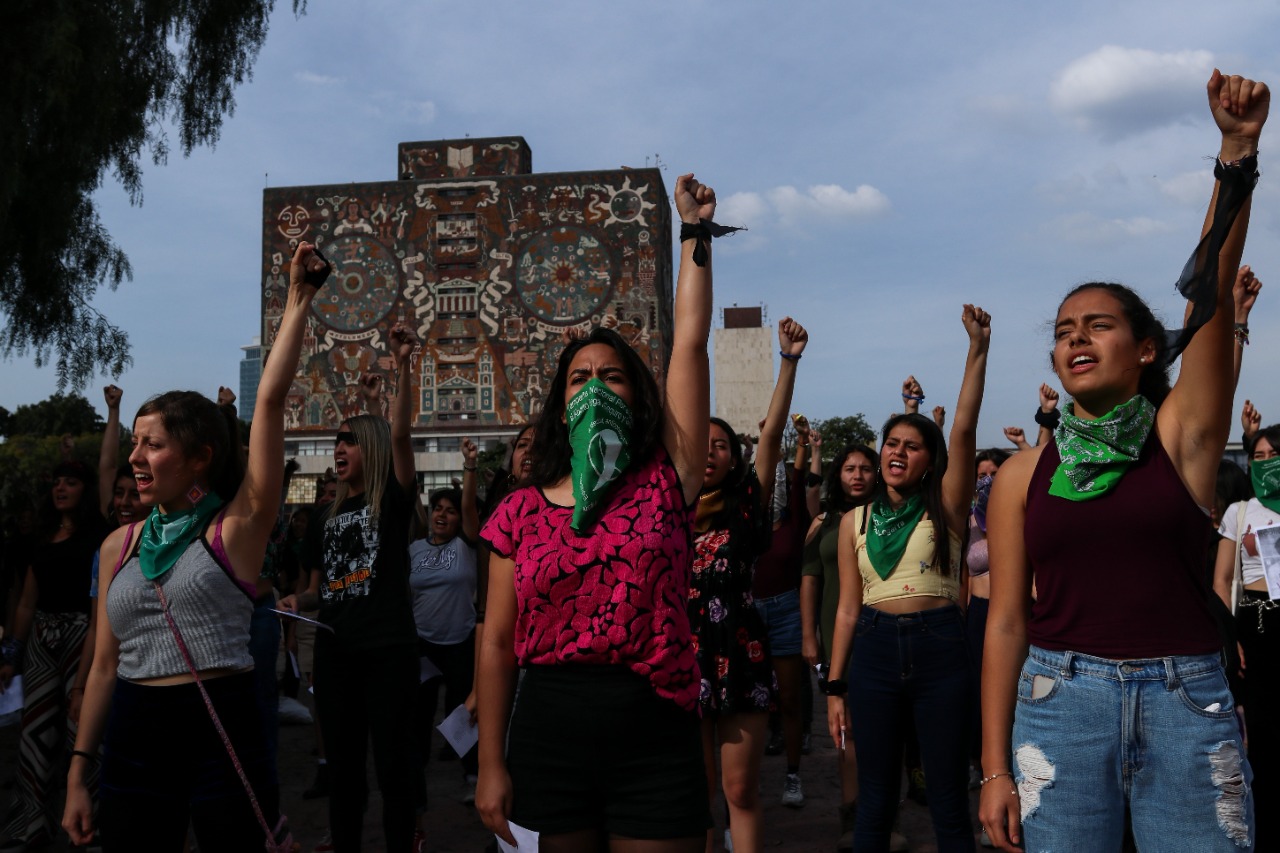 mujeres alzan sus puños en protesta por la violencia de genero en la unam