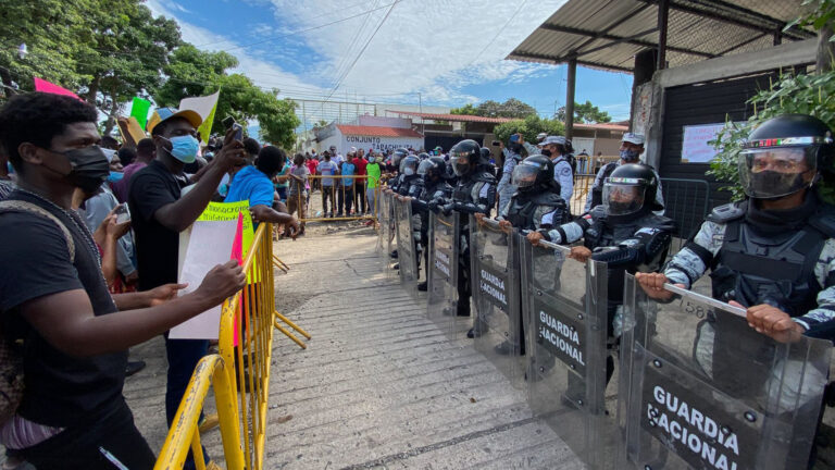 foto de migrantes frente a una fila de integrantes de la guardia nacional